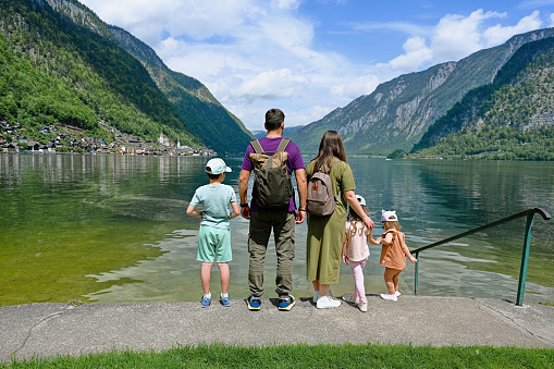 Back of family with three children over Austrian alps lake in Hallstatt, Salzkammergut, Austria.