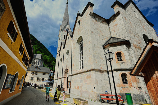 Mother with baby carriage and children walking near church at Hallstatt, Austria.