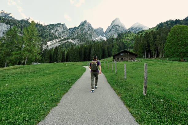Back of man with backpack walking in mountains at Vorderer Gosausee, Gosau, Upper Austria.