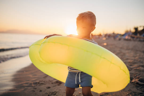 istock Little boy playing with inflatable ring on the beach during the sunset 1427931629