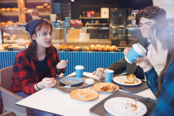 istock Teenagers eating and drinking at the table in cafeteria 1427934573