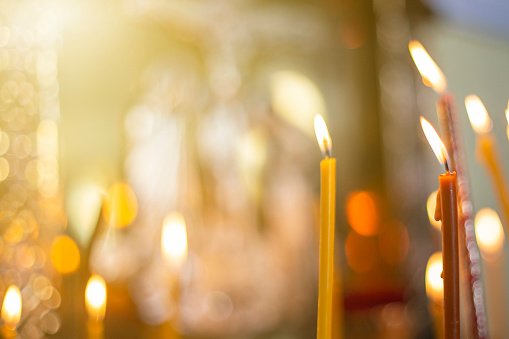 velas de iglesia de cerca, contra el fondo de una cruz religiosa especialmente borrosa photo