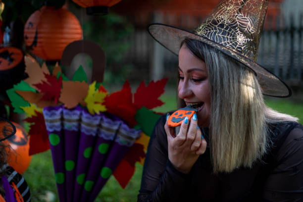 istock A woman eats gingerbread decorated for Halloween. 1427934825