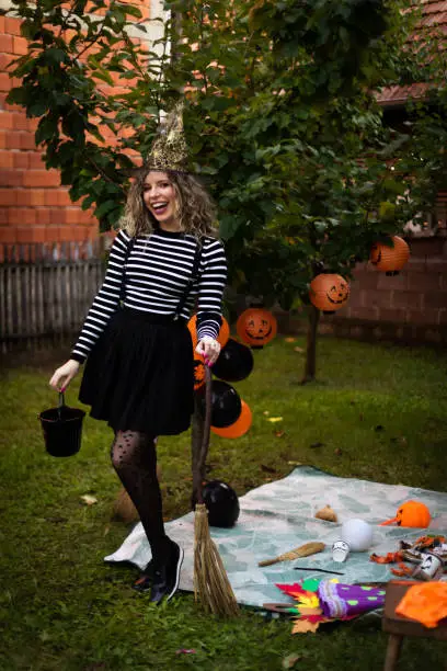 Photo of The woman is wearing a witch's costume. She is celebrating Halloween.
