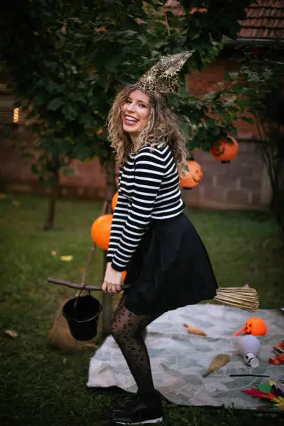 Photo of The witch is ready to fly! It's Halloween party. The woman is dressed as a witch.