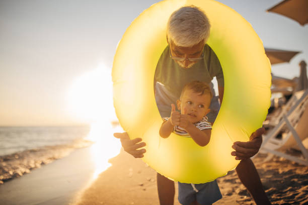 istock Grandfather and grandson playing with inflatable ring on the beach 1427940027