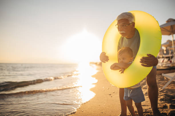 istock Grandfather and grandson playing with inflatable ring on the beach 1427940147