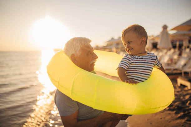 istock Grandfather and grandson playing with inflatable ring on the beach 1427940807