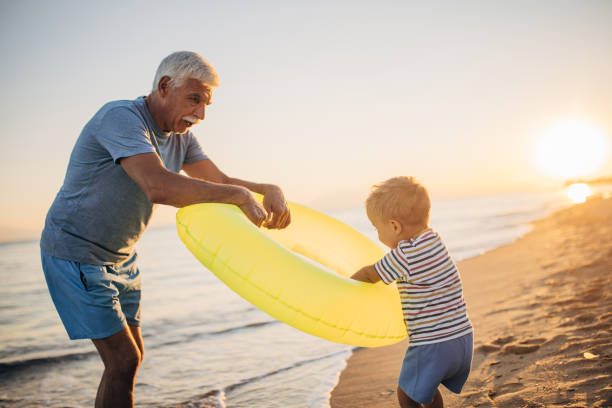 istock Grandfather and grandson playing with inflatable ring on the beach 1427940928
