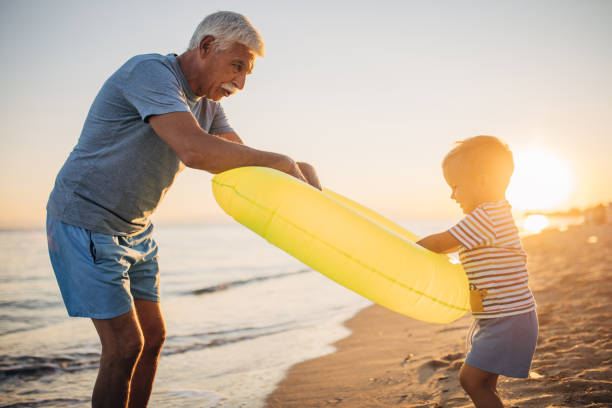 istock Grandfather and grandson playing with inflatable ring on the beach 1427940954