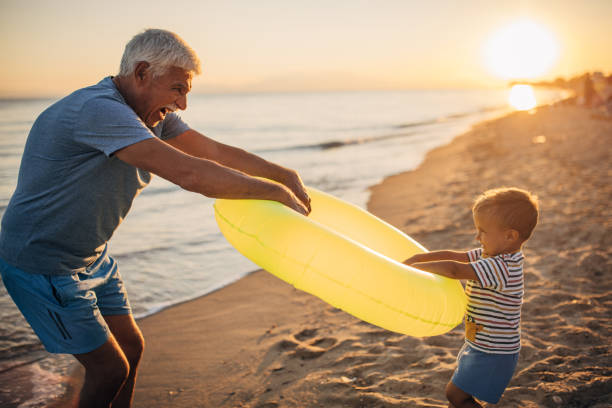 istock Grandfather and grandson playing with inflatable ring on the beach 1427941030