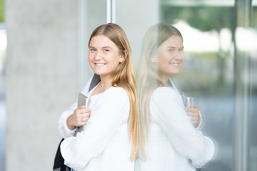 Portrait of cheerful university student girl reflected on wall