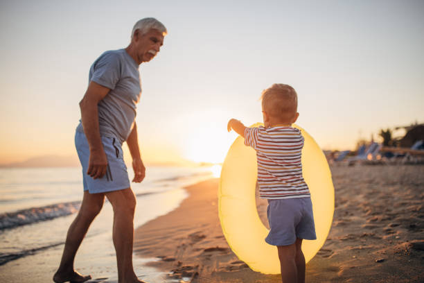 istock Grandfather and grandson playing with inflatable ring on the beach 1427945940
