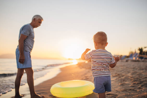 istock Grandfather and grandson playing with inflatable ring on the beach 1427945966