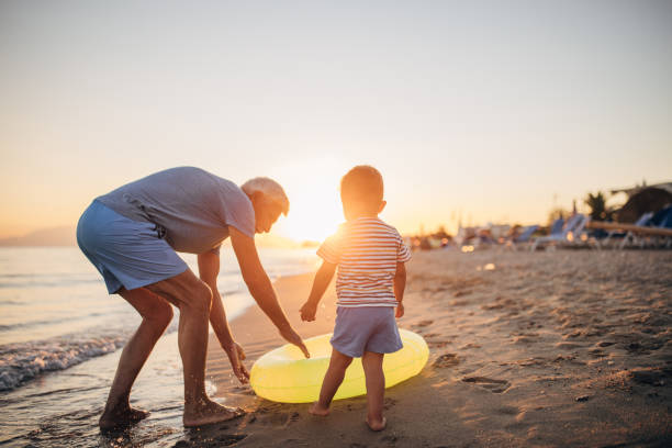istock Grandfather and grandson playing with inflatable ring on the beach 1427946018