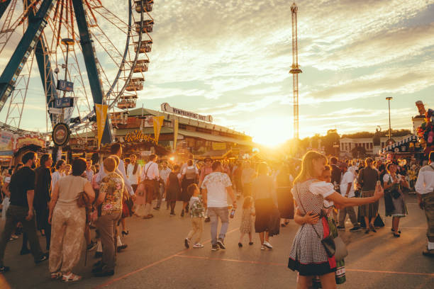 Munich, Germany - September 29, 2016: Visitors Walking Through Oktoberfest in Munich, Germany. The woman wearing typical dirndl and the men lederhosen - the traditional bavarian clothing. The Oktoberfest is the biggest beer festival of the world.
