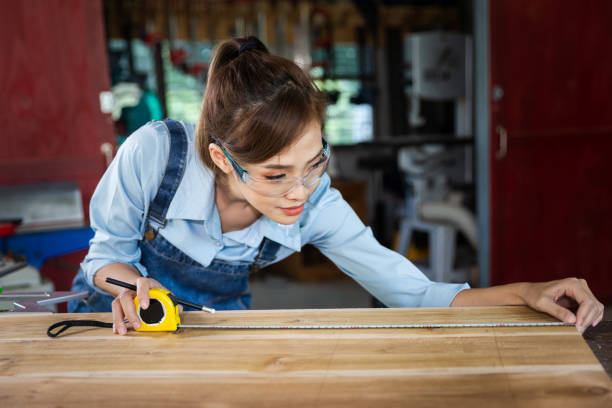 istock happy attractive hardworking middle aged professional female carpenter worker looking and choosing wood in the workshop. 1427951127