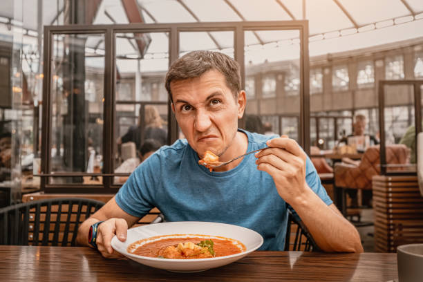 dissatisfied unhappy customer of the restaurant sniffs the disgusting smell of a bowl of soup with spoiled ingredients and is going to complain to the chef dissatisfied unhappy customer of the restaurant sniffs the disgusting smell of a bowl of soup with spoiled ingredients and is going to complain to the chef ugly soup stock pictures, royalty-free photos & images