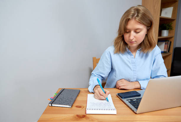 istock Young happy woman sitting at desk, working on computer at home. 1427956844