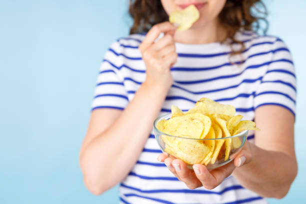 Young woman with chips on blue background stock photo