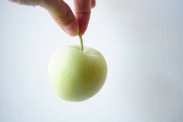 istock Green apple in female hand on white background 1427958189