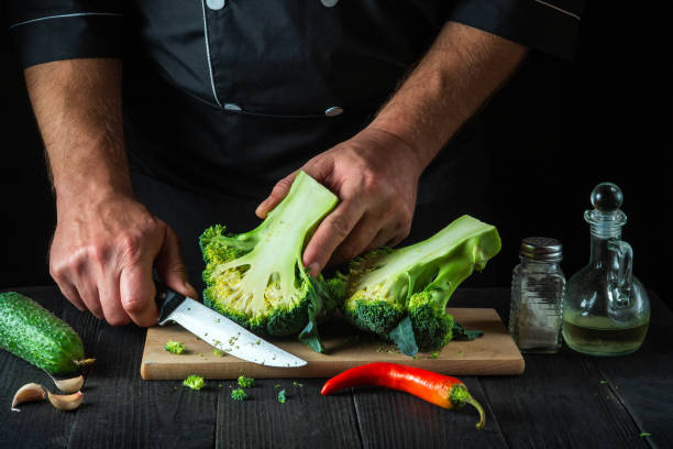 istock The chef cuts fresh Broccoli with a knife for salad on vintage kitchen table with fresh vegetables. Cooking and restaurant or cafe concept 1427959771