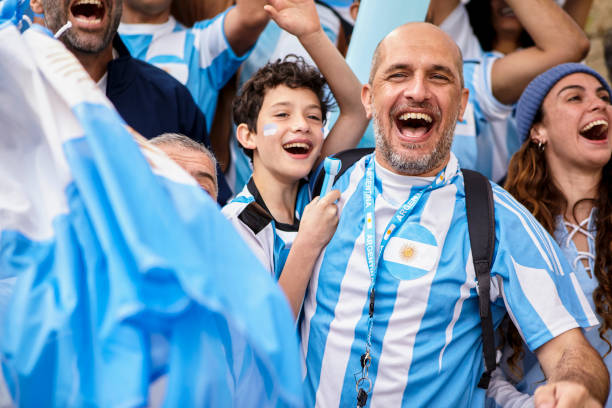 padre e hijo argentinos abrazados y animando mientras ven el partido de fútbol - argentina mundial fotografías e imágenes de stock