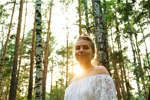 A young woman in the forest enjoys nature, air, sunlight. The concept of unity with nature.