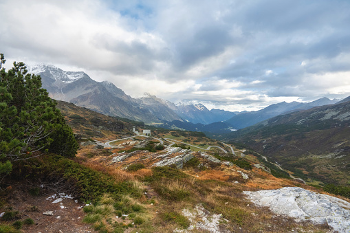 panoramic view from peak of the san Bernardino pass in the Swiss alps to the mountain range of the Graubünden canton, concrete ventilation shaft towers of the Tunnel system in the middle
