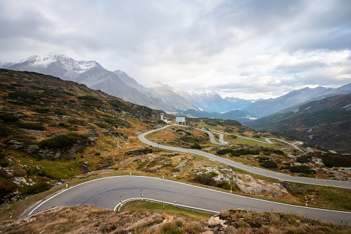 panoramic view from peak of the san Bernardino pass in the Swiss alps to the mountain range of the Graubünden canton, concrete ventilation shaft towers of the Tunnel system in the middle