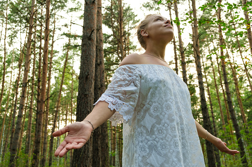 Enjoying the nature. Young woman arms raised enjoying the fresh air in green forest