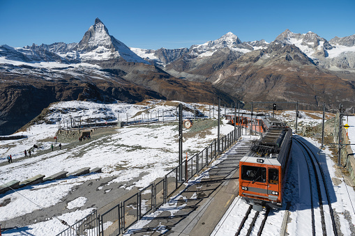 high angle view on red train coming up mountain in the swiss alps with Matterhorn in the background
