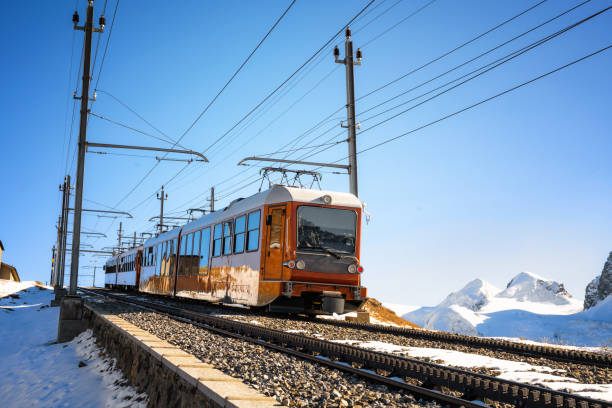 low angle view on red train coming down mountain in the swiss alps with mountain range in the background