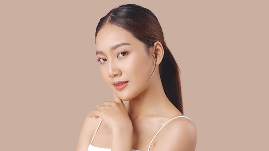 Foto de estudio de una hermosa joven asiática con piel limpia y fresca sobre fondo marrón, cuidado facial, tratamiento facial, cosmetología, belleza y spa. photo