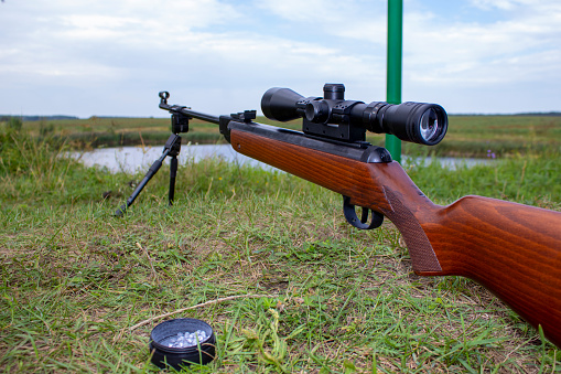 Pneumatic rifle for shooting with an optical sight on the background of grass on the hunt.