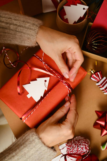 emballer des boîtes de noël et du nouvel an avec des cadeaux. enveloppe rouge pour les vœux. matériel d’emballage, jouets de noël, canne douce, rubans et lumières de noël. vue plate de dessus. joyeuses fêtes! - handmade paper paper homemade craft photos et images de collection