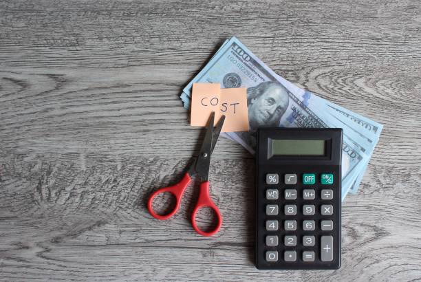 Scissor, calculator, money and note with text COST. stock photo