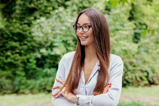 Portrait of a young smiling ukrainian girl in glasses against the background of nature, trees, building facade. Happy student girl look at copy space. education abroad.