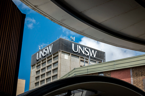 Sydney, Australia - Oct 29, 2020: View of the John Goodsell Building of University of New South Wales, with UNSW lettering at top. Building framed by nearby structures. Blue sky with white clouds.