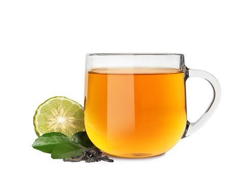 Glass cup of bergamot tea and fresh fruit on white background