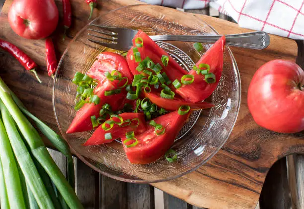 Homemade fresh marinated tomato salad. Made with beefsteak tomatoes from the garden, chives and olive oil. Healthy snack or side dish