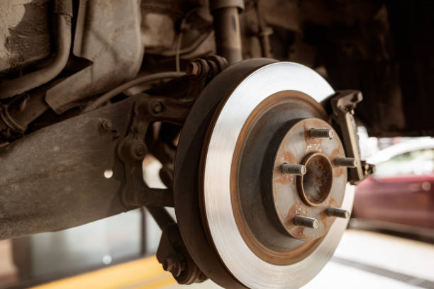 istock Car disc brake system. Car suspension in process of new tire replacement at garage workshop. Car disc brake mechanic check and repair. Disk break rotor. Car in change tire process at service station. 1427972237