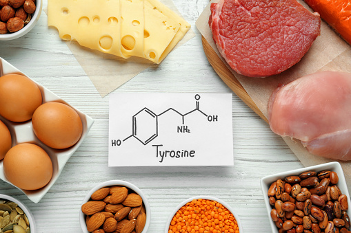 Different fresh products and paper with Tyrosine chemical formula on white wooden table, flat lay. Sources of essential amino acids