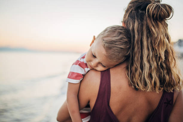 istock A mother carrying her son on the beach 1427974386