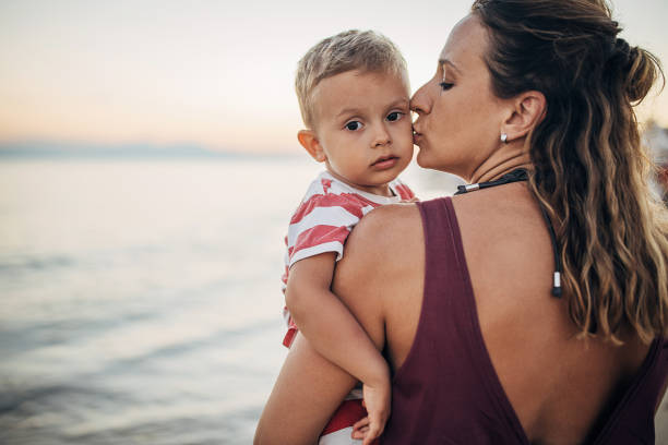 istock A mother carrying her toddler on the beach 1427974581