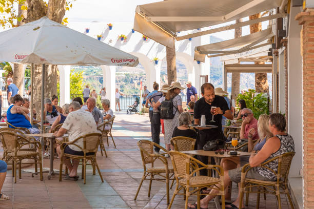 Customers sitting enjoying meals and drinks in a busy restaurant in Nerja, white town in province Málaga, Spain