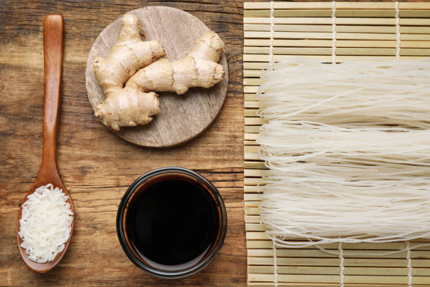 istock Flat lay composition with uncooked rice noodles, soy sauce and ginger on wooden table 1427976305