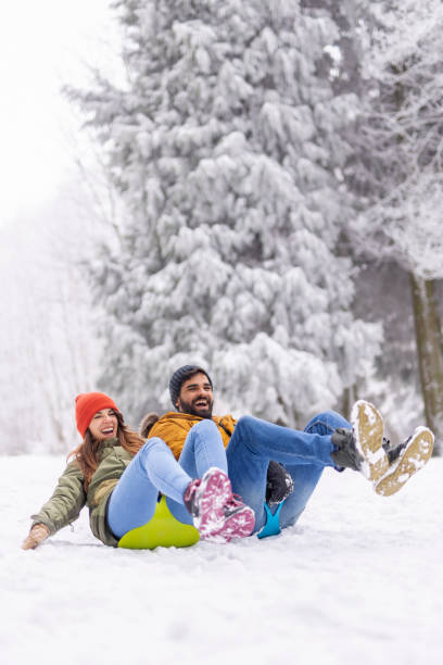istock Couple sliding down the hill in the snow while on winter vacation 1427976486