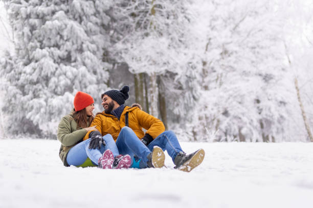 istock Couple sitting and hugging in the snow while on winter vacation 1427976653