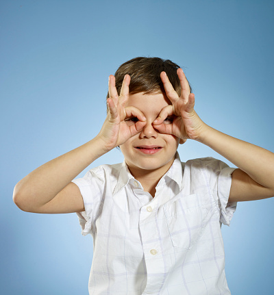 Cute boy making a hand gesture and making binoculars with his hands